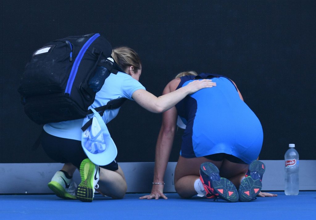 Coco Vandeweghe of the US (R) receives assistance due to illness while playing against Italy's Roberta Vinci in their women's singles first round match on day one of the Australian Open tennis tournament in Melbourne on January 16, 2017. / AFP / WILLIAM WEST / --IMAGE RESTRICTED TO EDITORIAL USE - STRICTLY NO COMMERCIAL USE-- (Photo credit should read WILLIAM WEST/AFP/Getty Images)