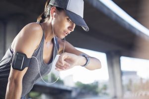 Woman looking at watch after exercising on city street